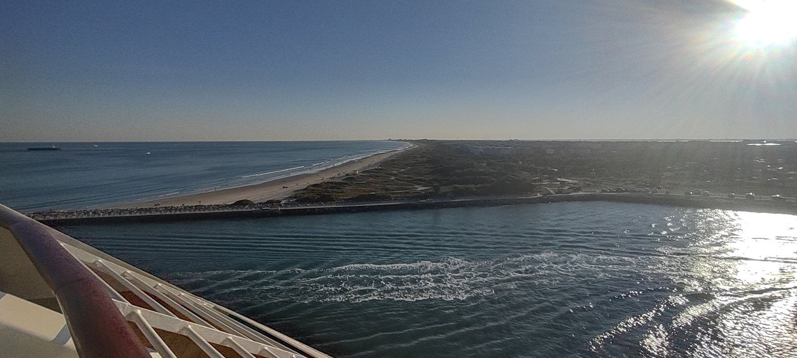 Sailing out of Port Canaveral past the jetty and the beach, late afternoon sun on the water