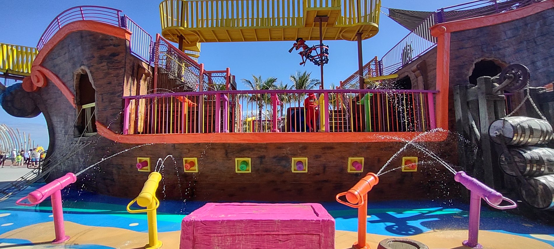 The free pirate ship playground at Perfect Day at CocoCay, a brightly painted wooden ship with water cannons in front of it
