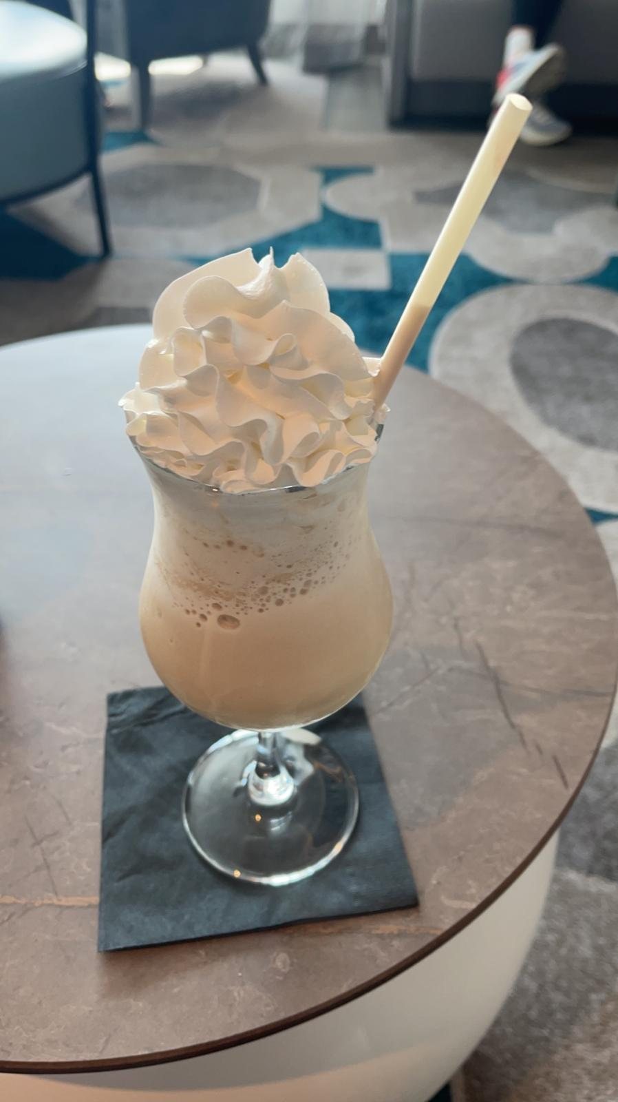 A tall frozen blended cocktail in a stemmed glass on a table aboard ship