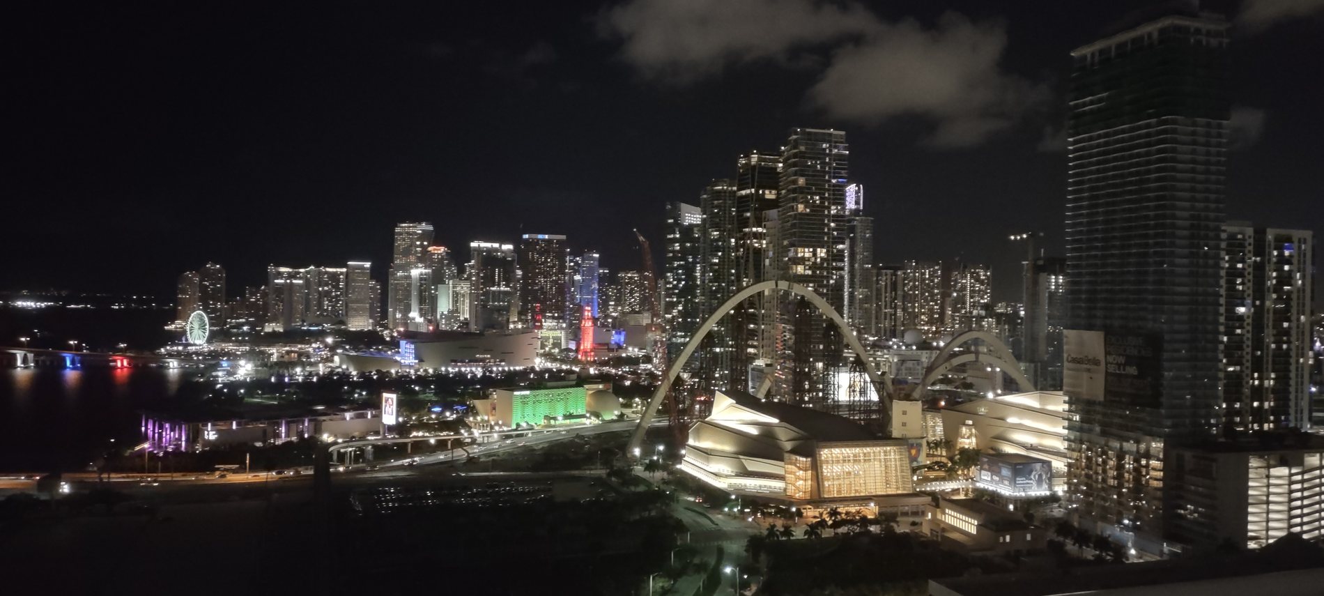 The Miami skyline at night seen wide from a cruise ship, lit towers and the illuminated observation wheel on the waterfront