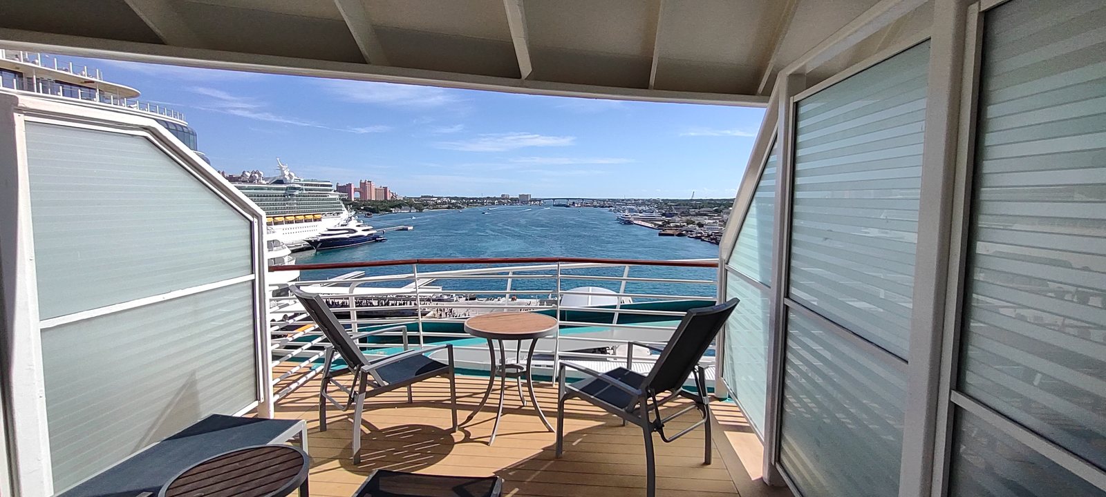 A cruise ship balcony with table and chairs, looking out over Nassau harbour