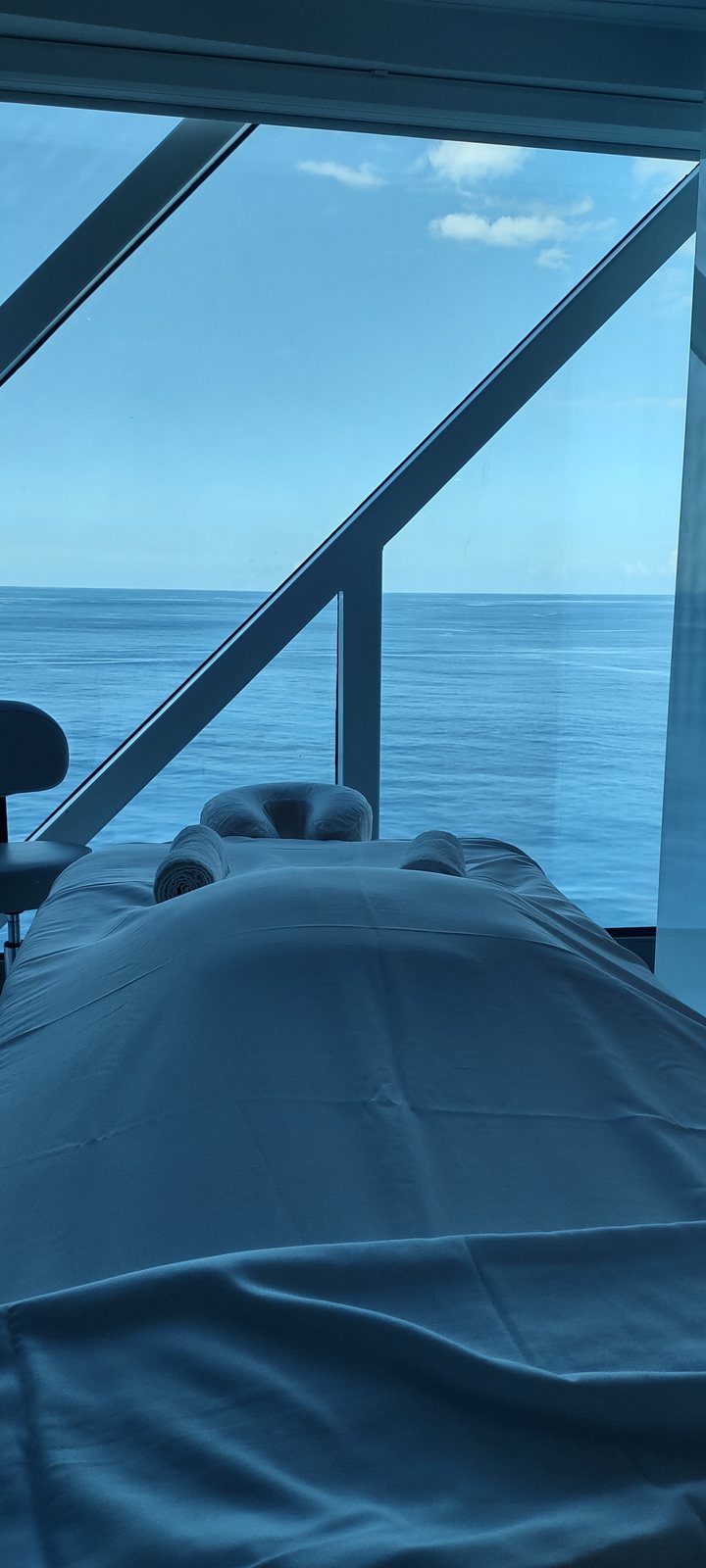 A treatment table beside a floor-to-ceiling window looking out at a flat calm sea